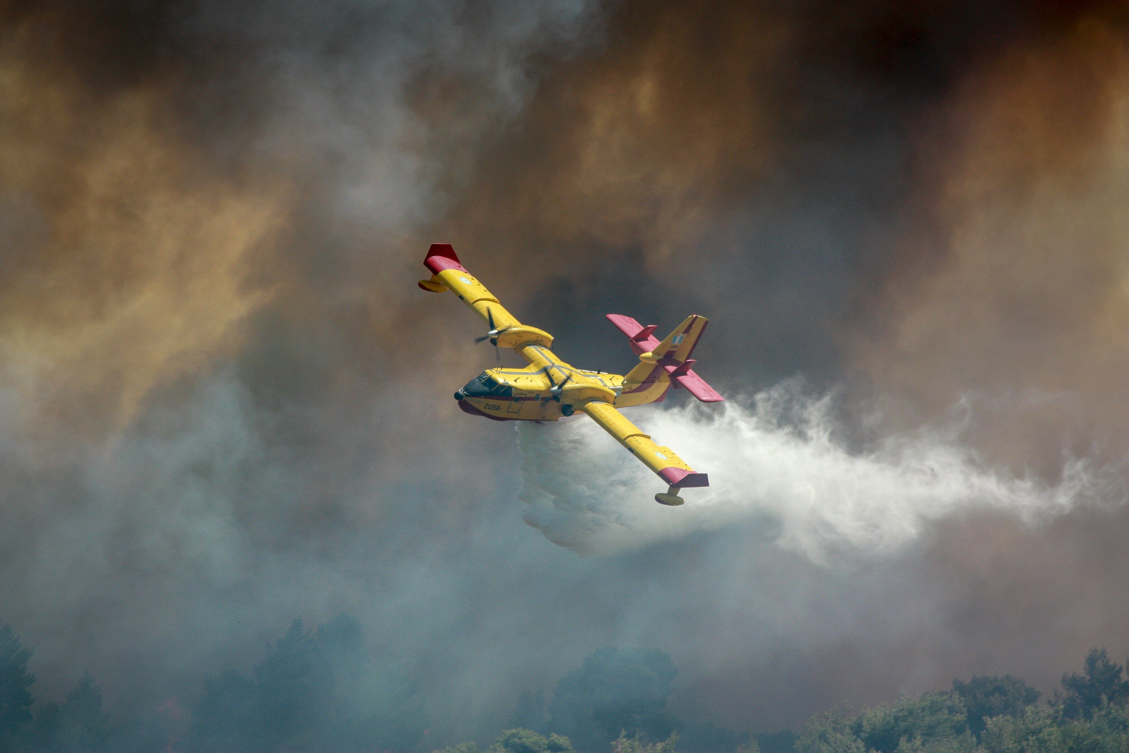 yellow airplane releasing water over wildfire