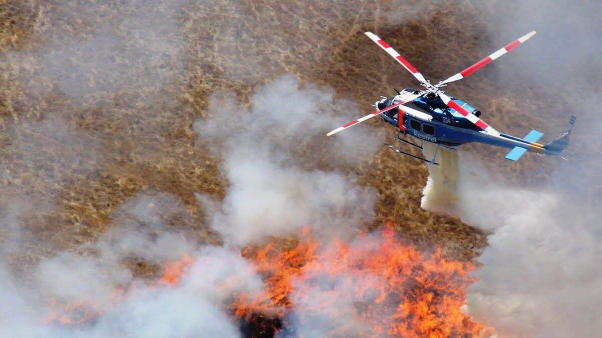 blue helicopter over wildfire