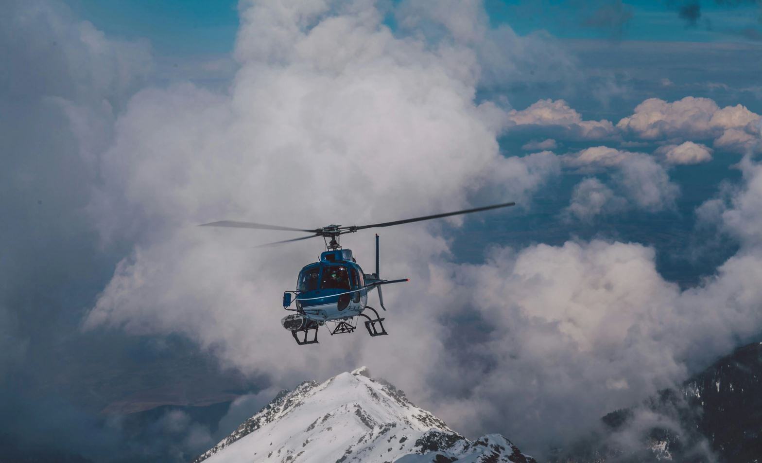 helicopter flying over snowy mountains